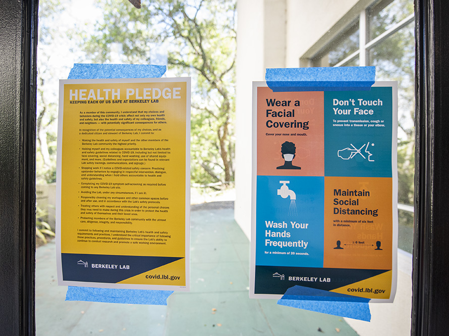 Signs noting new COVID safety procedures taped to a window.