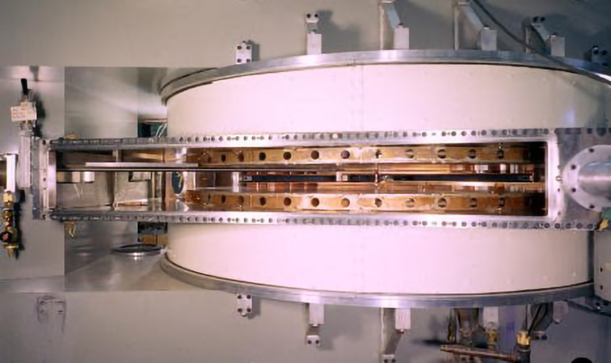 A large cylindrical scientific apparatus with a metal frame and multiple components, including a central section with numerous holes and rods