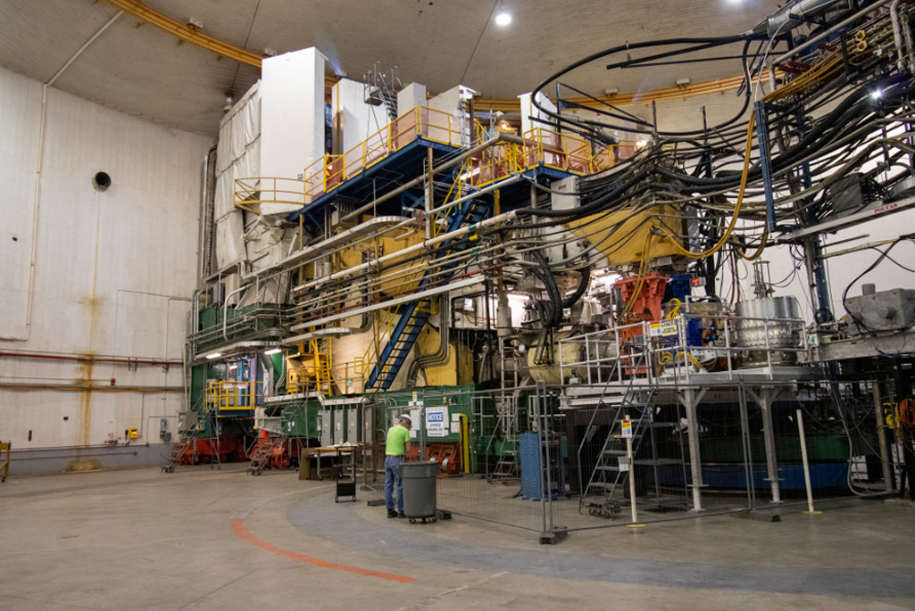 A worker stands in front of a large industrial structure