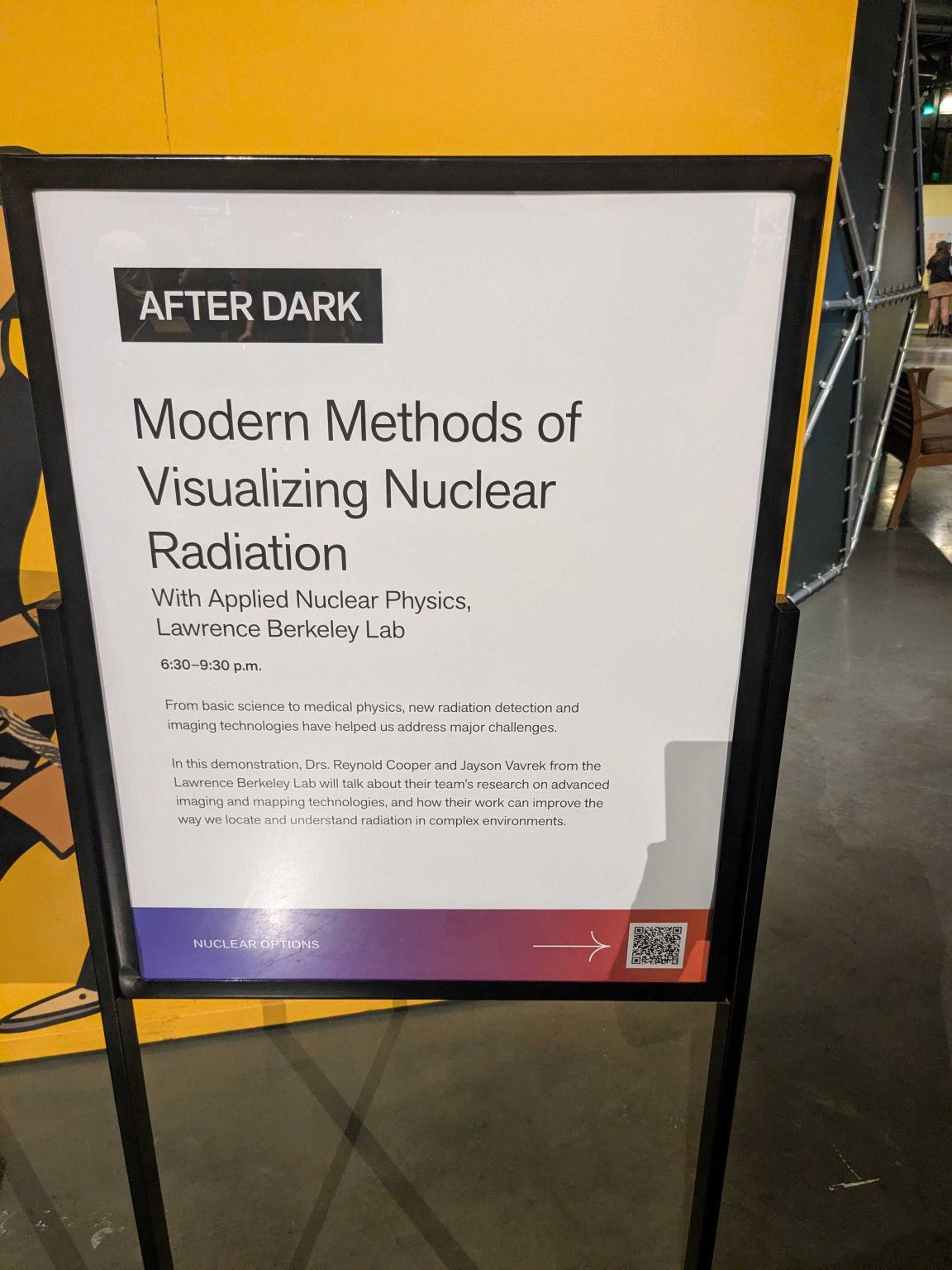 Image showing a sign reading "Modern Methods of Visualizing Nuclear Radiation With Applied Nuclear Physics, Lawrence Berkeley Lab 6:30-9:30 p.m. From basic science to medical physics, new radiation detection and imaging technologies have helped us address major challenges. In this demonstration, Drs. Reynold Cooper and Jayson Vavrek from the Lawrence Berkeley Lab will talk about their team's research on advanced imaging and mapping technologies, and how their work can improve the way we locate and understand radiation in complex environments."