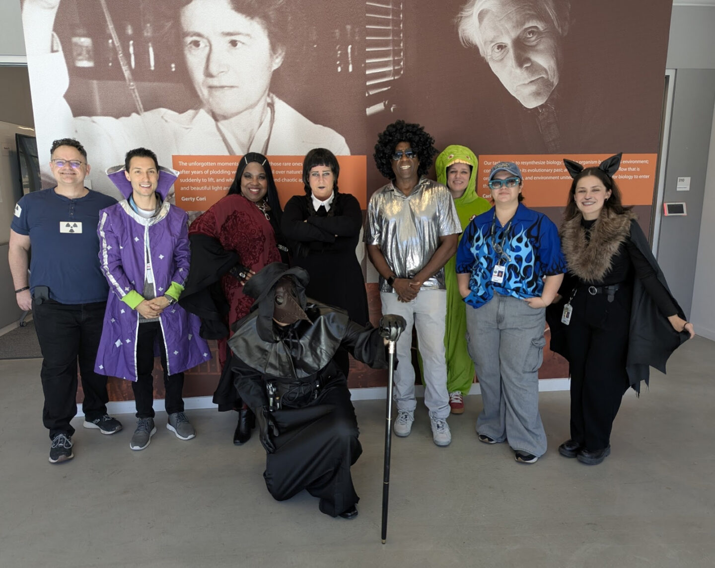 10 people in costume in front of a mural.