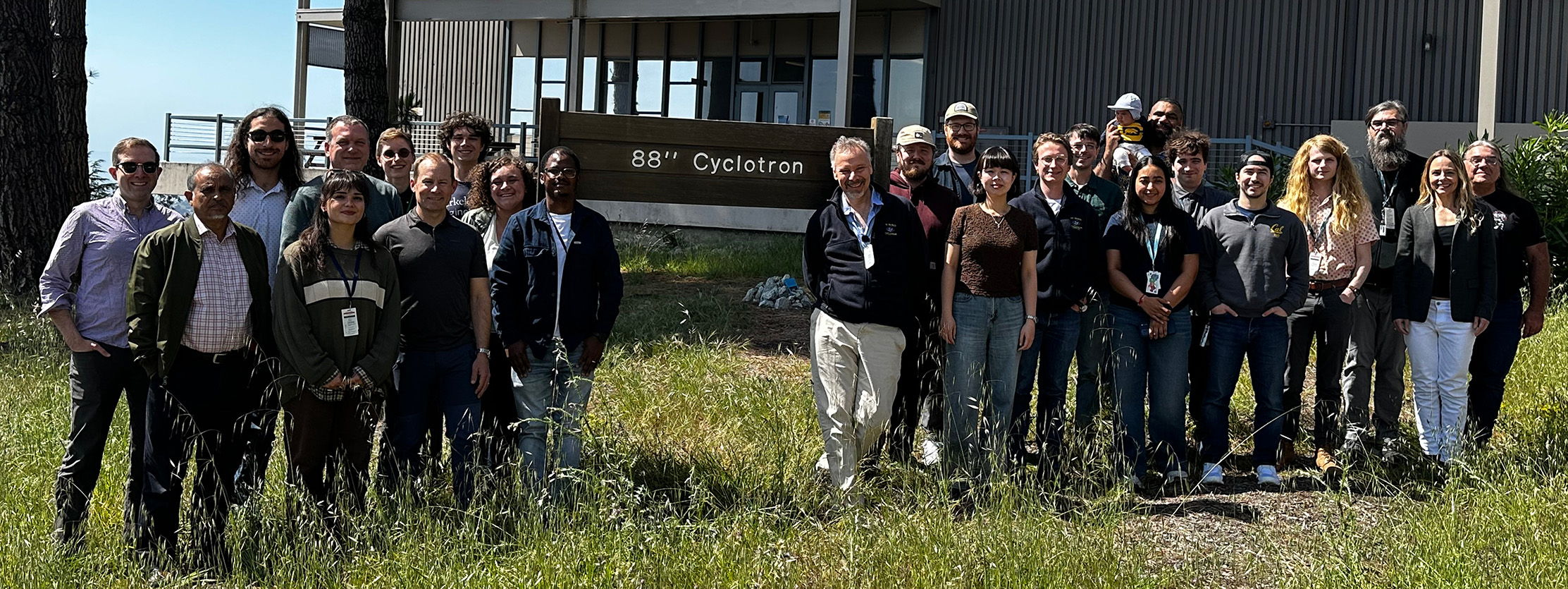 A group of people standing on grass in front of sign that read 88-Inch Cyclotron