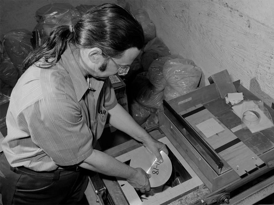 The image shows scientist Al Smith in a room with thick concrete walls, loading a disk into a table-top experimental device.
