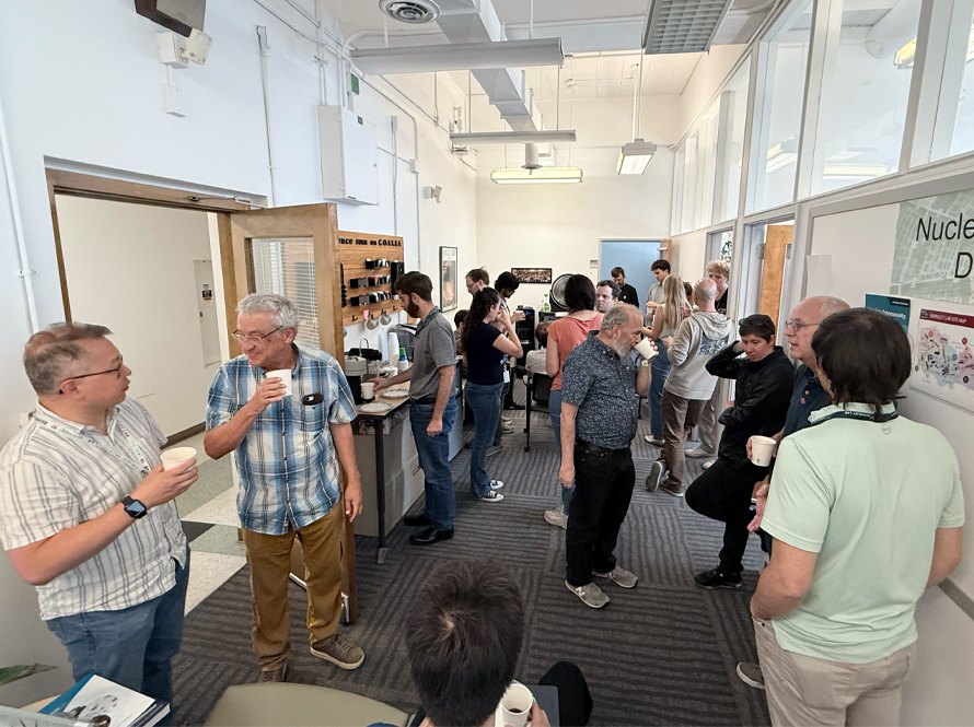 A group of people standing around drinking coffee and discussing science.